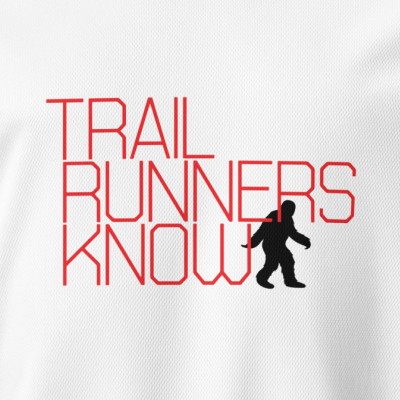 Female mannequin wearing a yellow tee shirt with graphics 'TRAIL RUNNERS KNOW' with the historic photo of a blurred Bigfoot looking back at her as she's running through the forest.